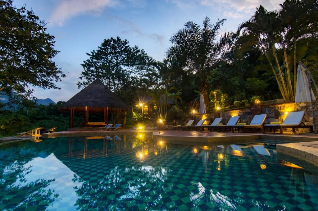 a pool at night with chairs and a gazebo at Hillside - Nature Lifestyle Lodge in Luang Prabang