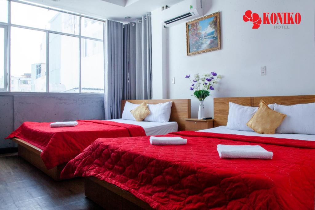 2 camas en una habitación de hotel con sábanas rojas en Koniko Hotel, en Ho Chi Minh