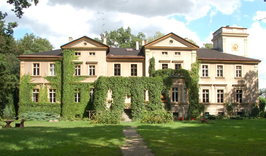 Una casa grande con hiedra en la parte delantera. en Pałac Baborówko, en Szamotuły