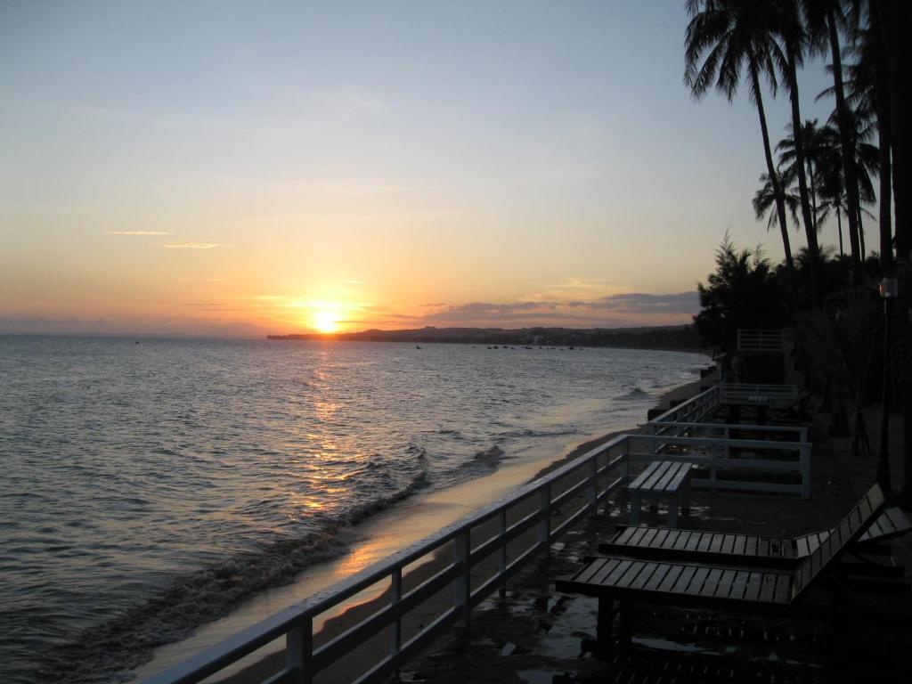 puesta de sol en la playa con bancos y palmeras en Mui Ne Resort, en Mui Ne