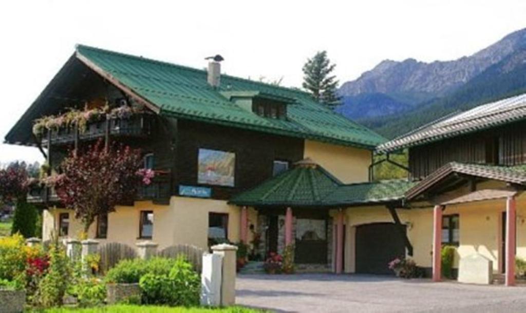 un gran edificio con techo verde y montañas de fondo en Pleiknerhof, en Leutasch