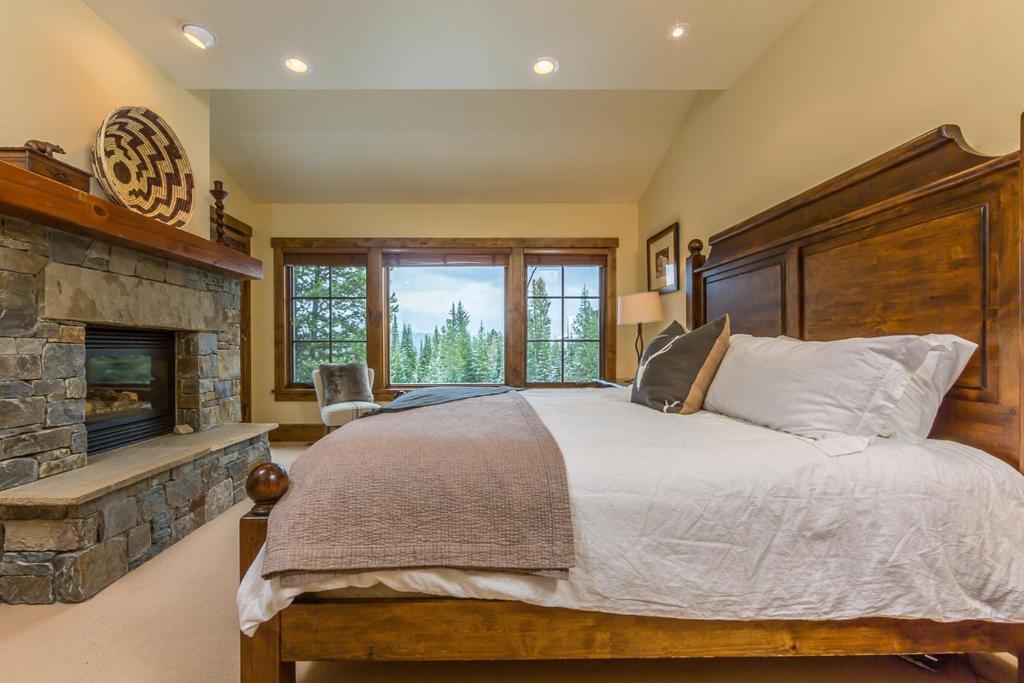 a bedroom with a large bed and a fireplace at Homestead Cabin 2 in Big Sky