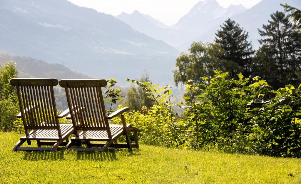 two chairs sitting in the grass with mountains in the background at Landhaus Maria Grün B&B in Feldkirch
