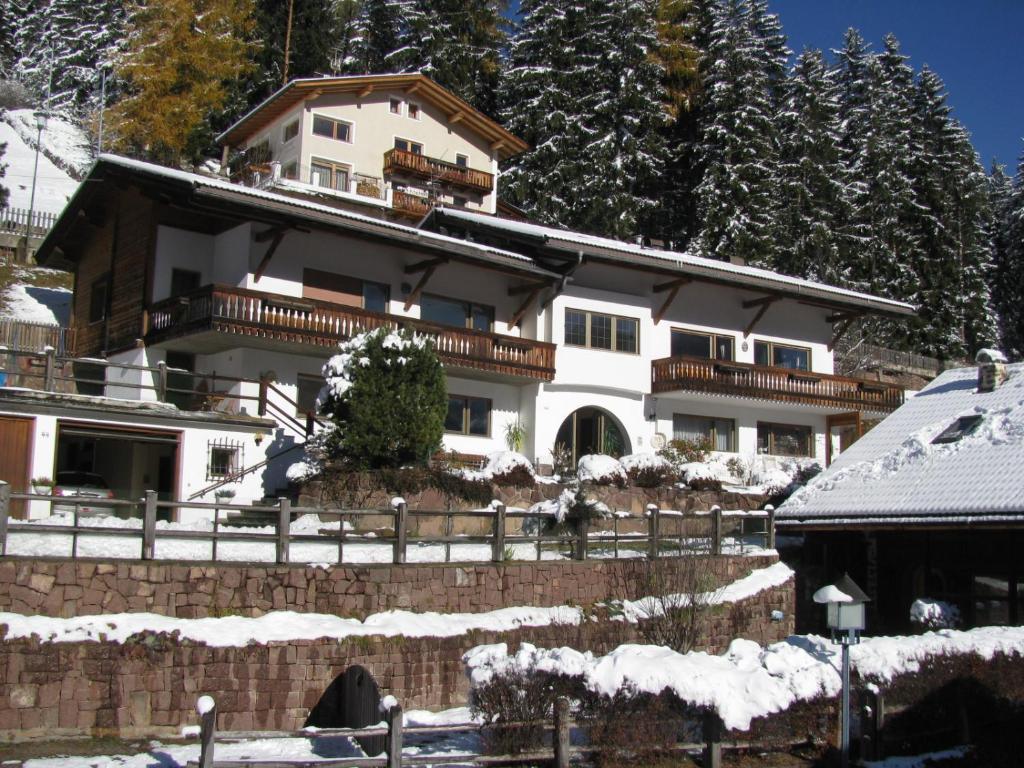 Une grande maison blanche avec de la neige au sol dans l'établissement Holiday Apartments Costanzi, à Ortisei