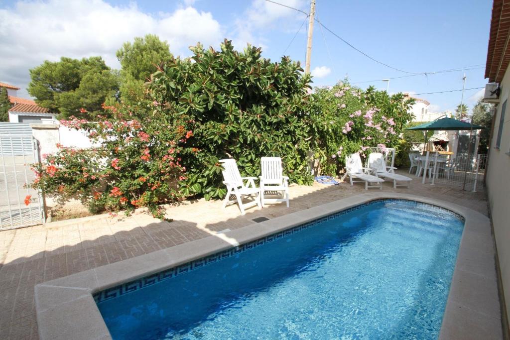 - une piscine avec des chaises, une table et un parasol dans l'établissement ARENDA Villa Berlin, à Miami Platja