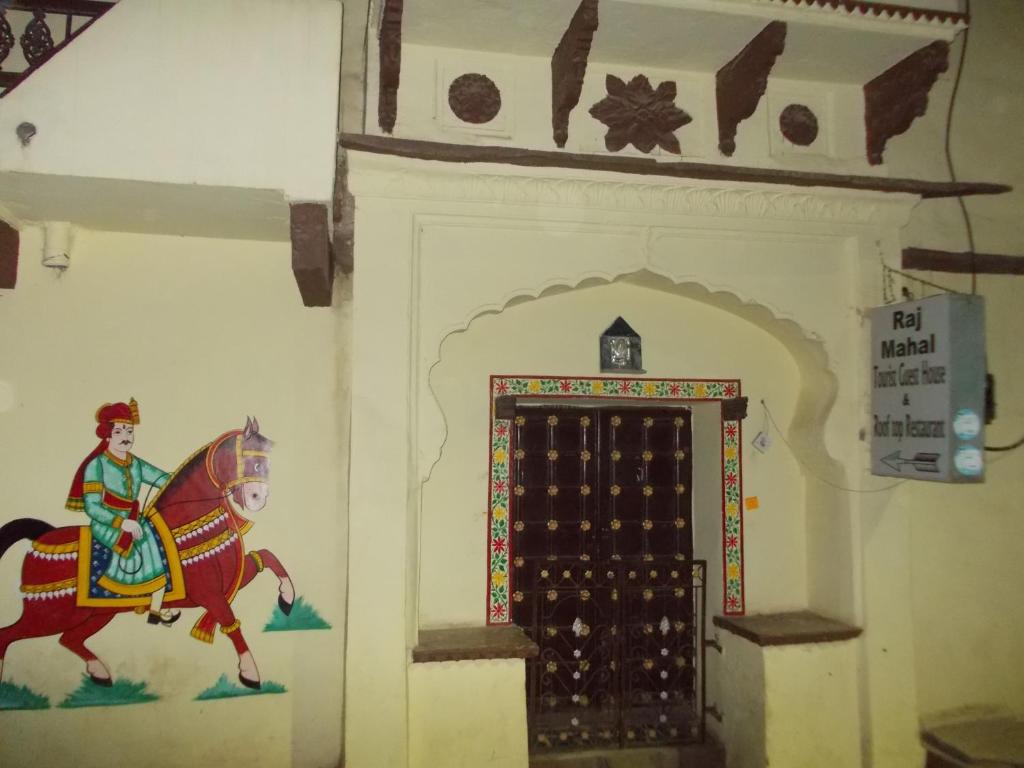 Un dipinto di un uomo che cavalca un cavallo accanto a una porta di Raj Mahal Guest House a Būndi