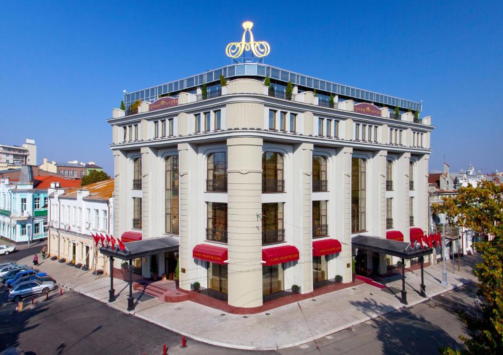 un edificio blanco con un reloj encima en Aleksandrovski Grand Hotel en Vladikavkaz