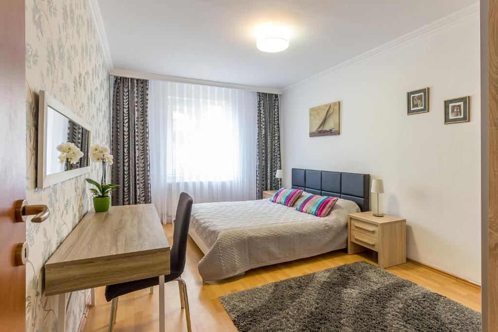 a bedroom with a bed and a table and a window at City Apartment Trifoiului in Cluj-Napoca