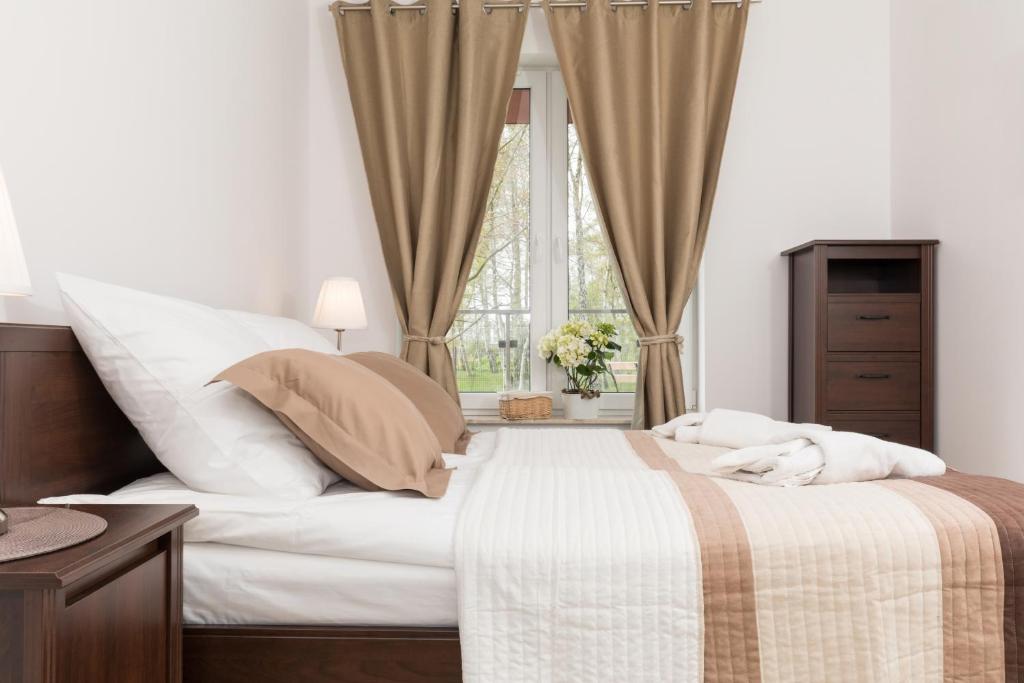 a bedroom with a large white bed with a window at Grace Apartment II in Kołobrzeg