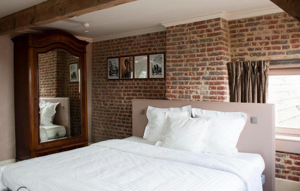 a bedroom with a white bed and a brick wall at Guesthouse Recour in Poperinge