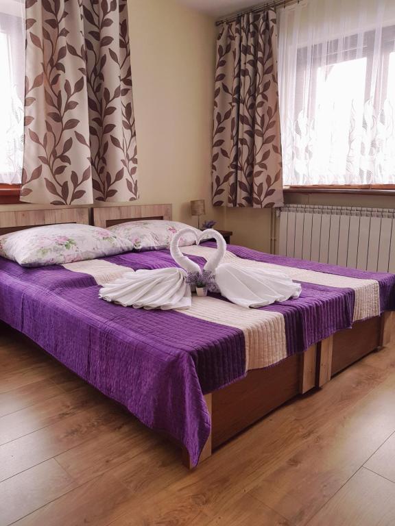a bed with purple sheets and white towels on it at Pokoje Gościnne Agusia in Zakopane