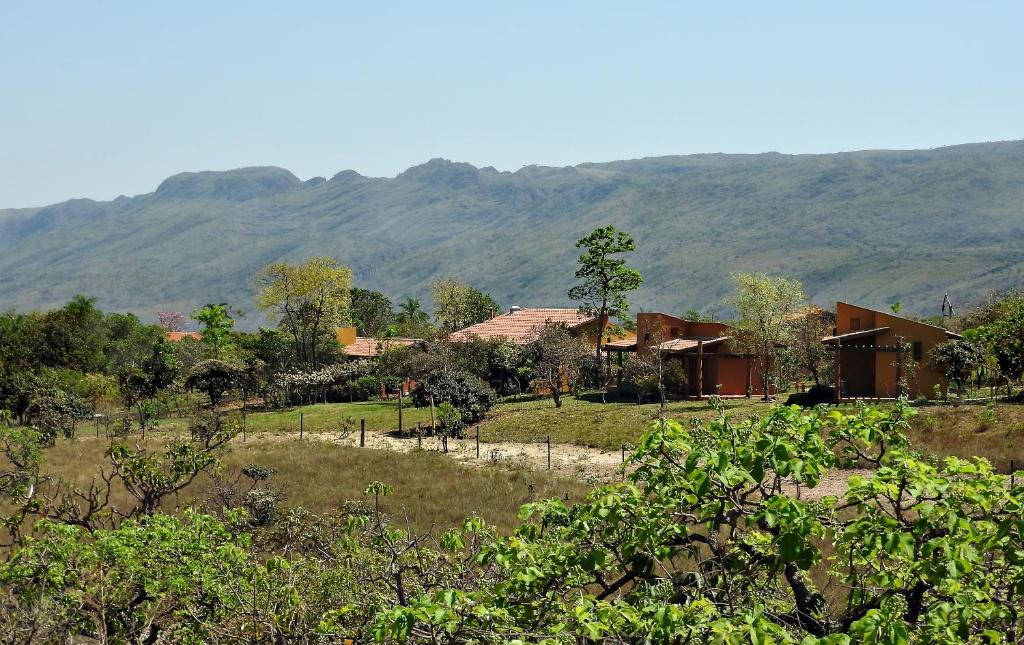 a house in a field with mountains in the background at Pousada Encantos do Cerrado in Delfinópolis
