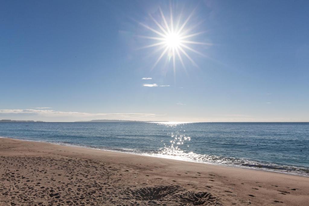 a beach with the sun shining over the ocean at Appartement Cannes vue mer in Cannes