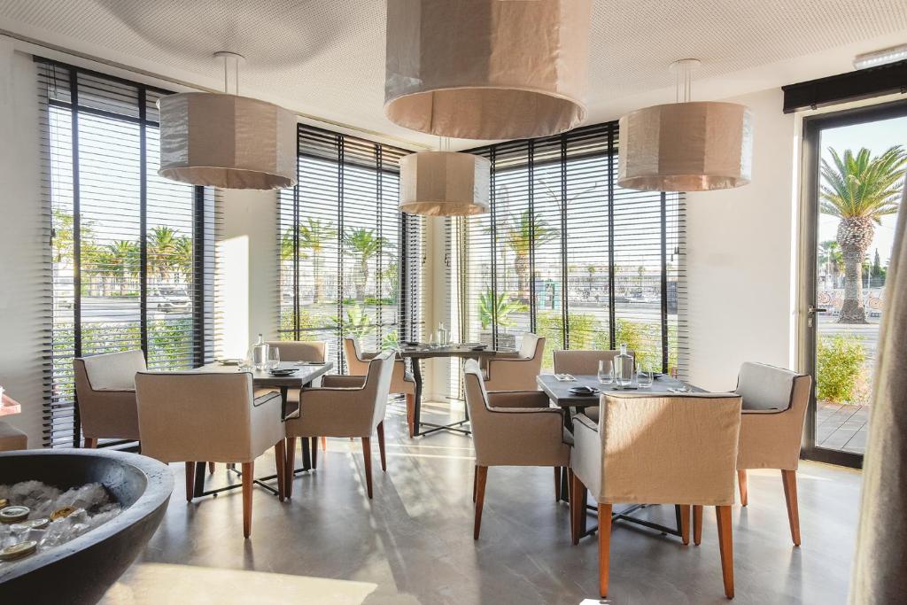 a dining room with tables and chairs and large windows at Lagos Avenida Hotel in Lagos