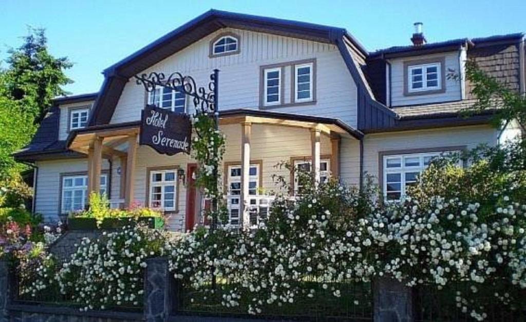 una casa grande con flores blancas delante en Hotel Serenade de Franz Schubert, en Frutillar