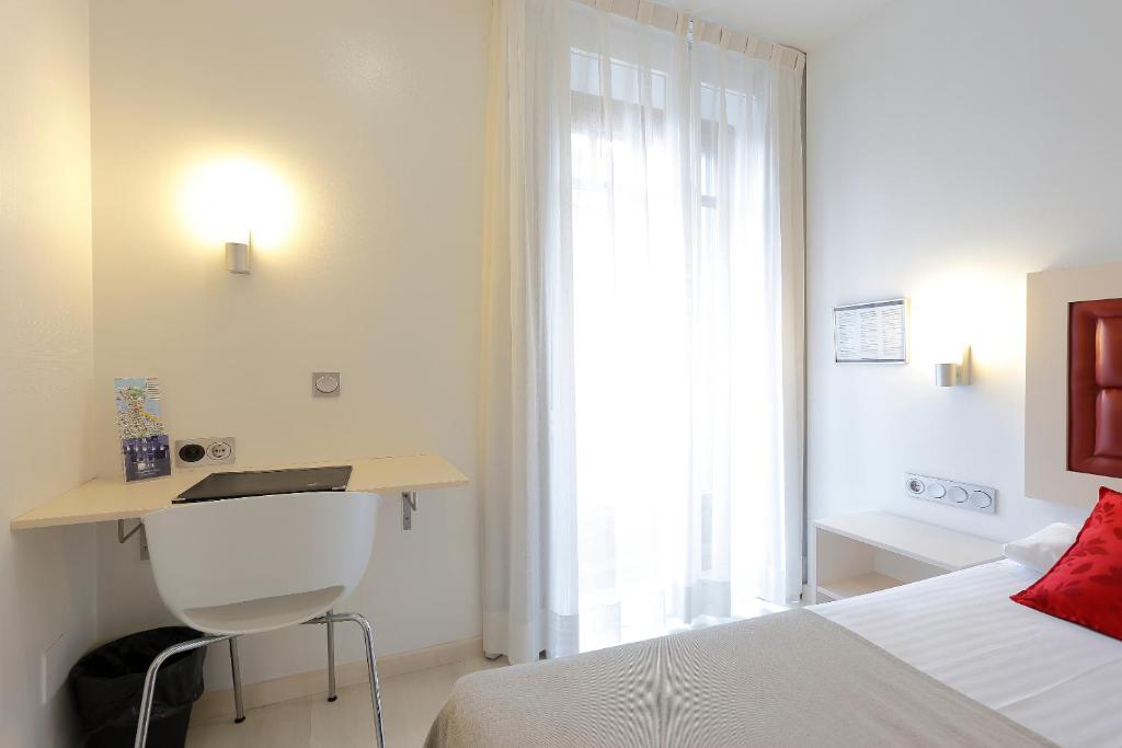 a bedroom with a bed and a desk and a window at Hotel Santa Rosa, Blue Hoteles in Gijón