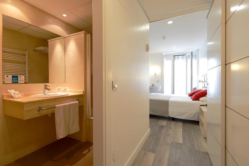 a bathroom with a sink and a bedroom with a bed at Hotel Santa Rosa, Blue Hoteles in Gijón