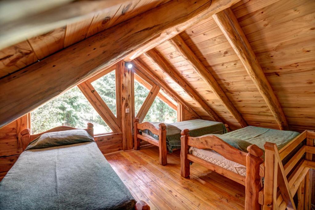 a log cabin with two beds and a window at Complejo Palo Quemado in El Hoyo