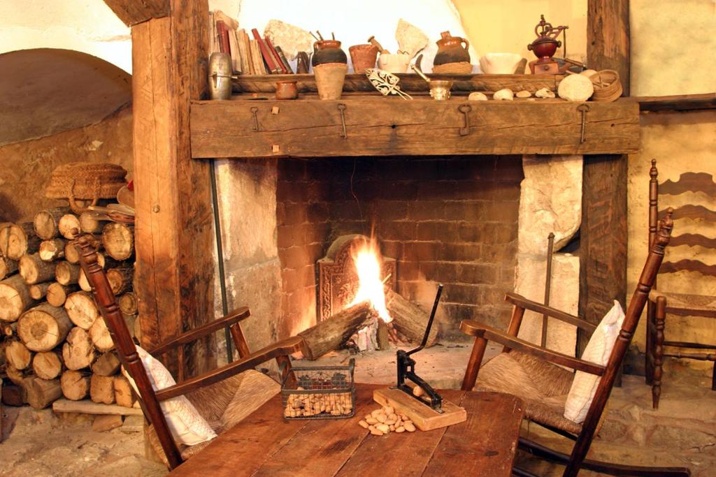 a fireplace with a fire in it with two chairs at Casa Rural Garrido in Ademuz