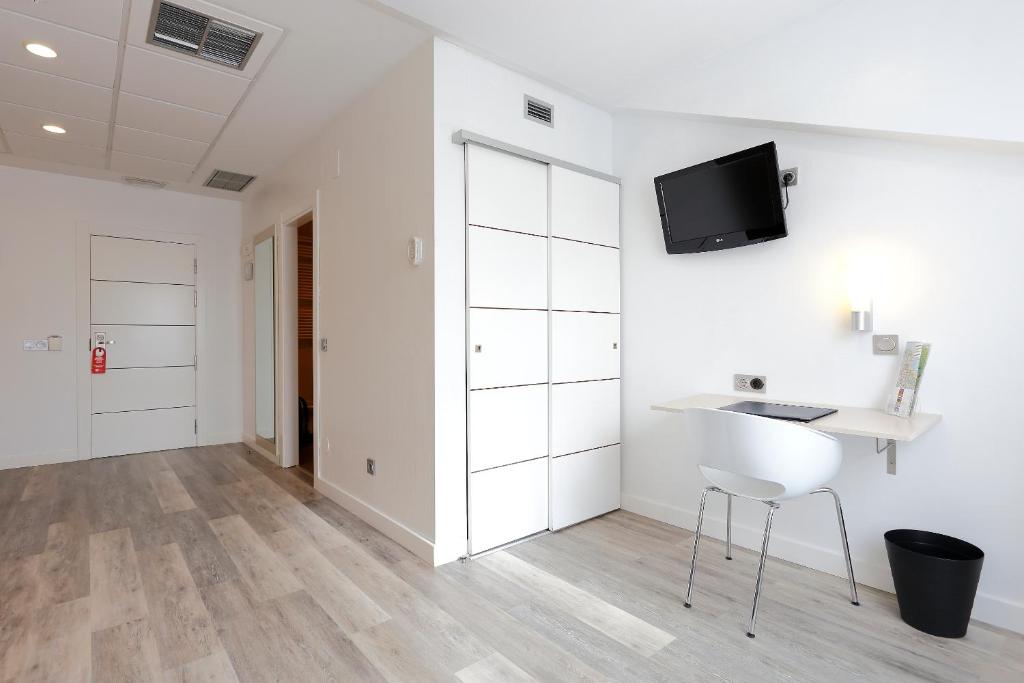 a white room with a desk and a tv on the wall at Hotel Santa Rosa, Blue Hoteles in Gijón