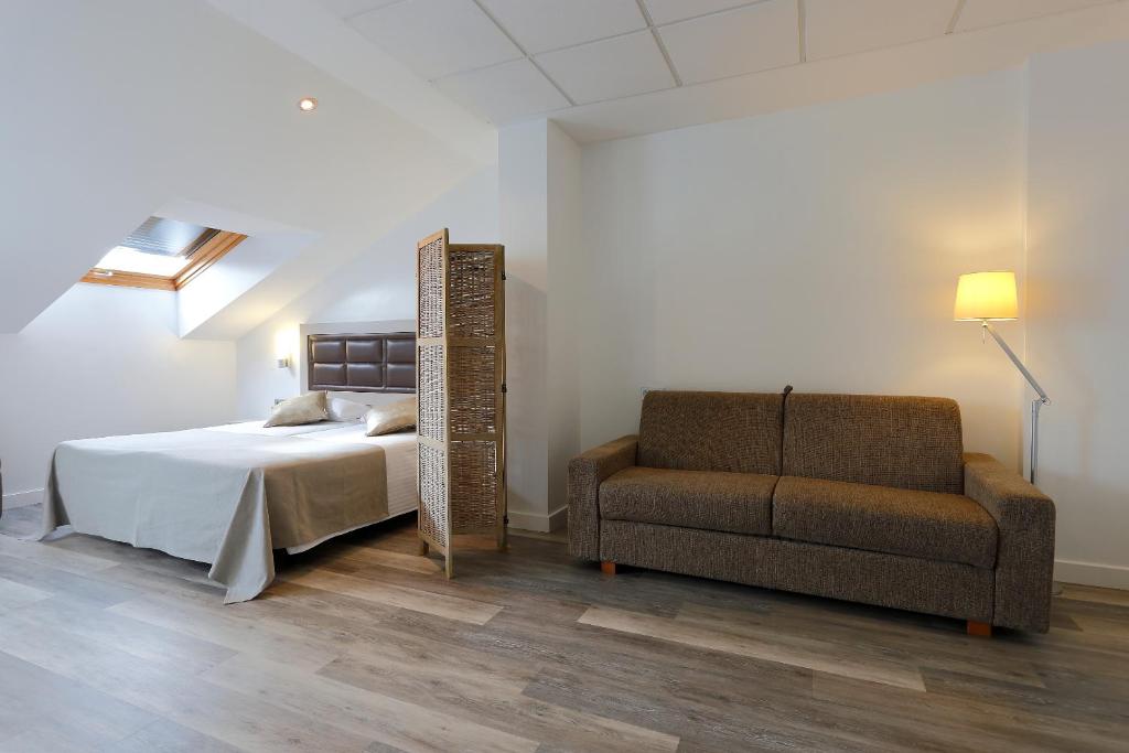 a bedroom with a bed and a couch and a mirror at Hotel Santa Rosa, Blue Hoteles in Gijón