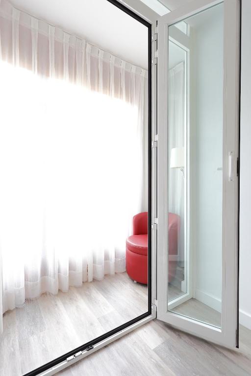a sliding glass door with a red chair in a room at Hotel Santa Rosa, Blue Hoteles in Gijón