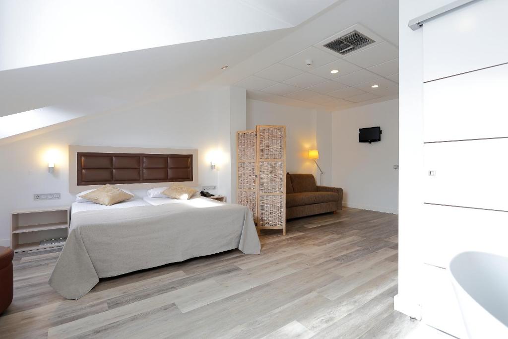 a white bedroom with a bed and a couch at Hotel Santa Rosa, Blue Hoteles in Gijón