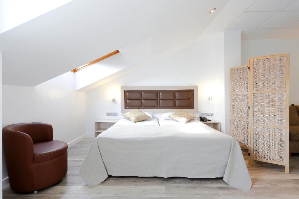 a white bedroom with a bed and a chair at Hotel Santa Rosa, Blue Hoteles in Gijón