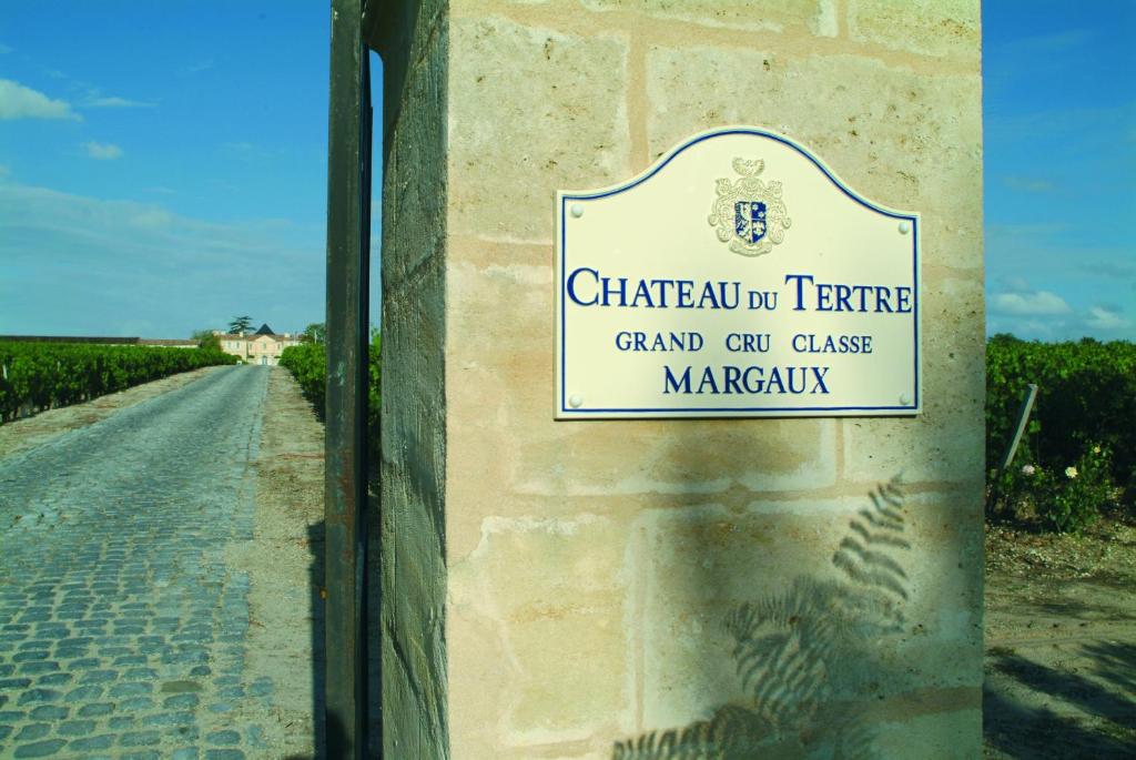 a sign on a wall next to a road at Château du Tertre in Arsac