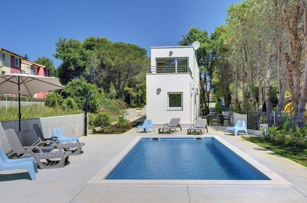 una piscina con sillas y una casa en Villa Chiara, en Premantura