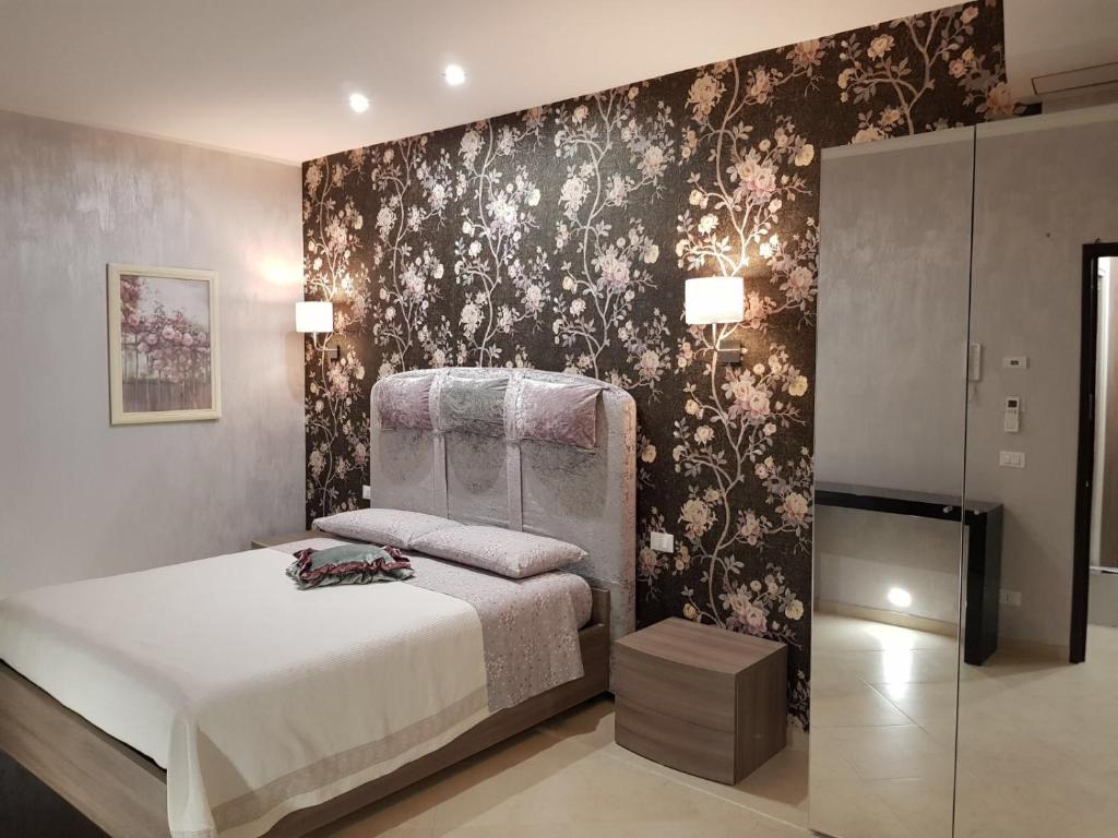 1 dormitorio con cama y pared con papel pintado con motivos florales en Le Cale' B&B, en San Severo
