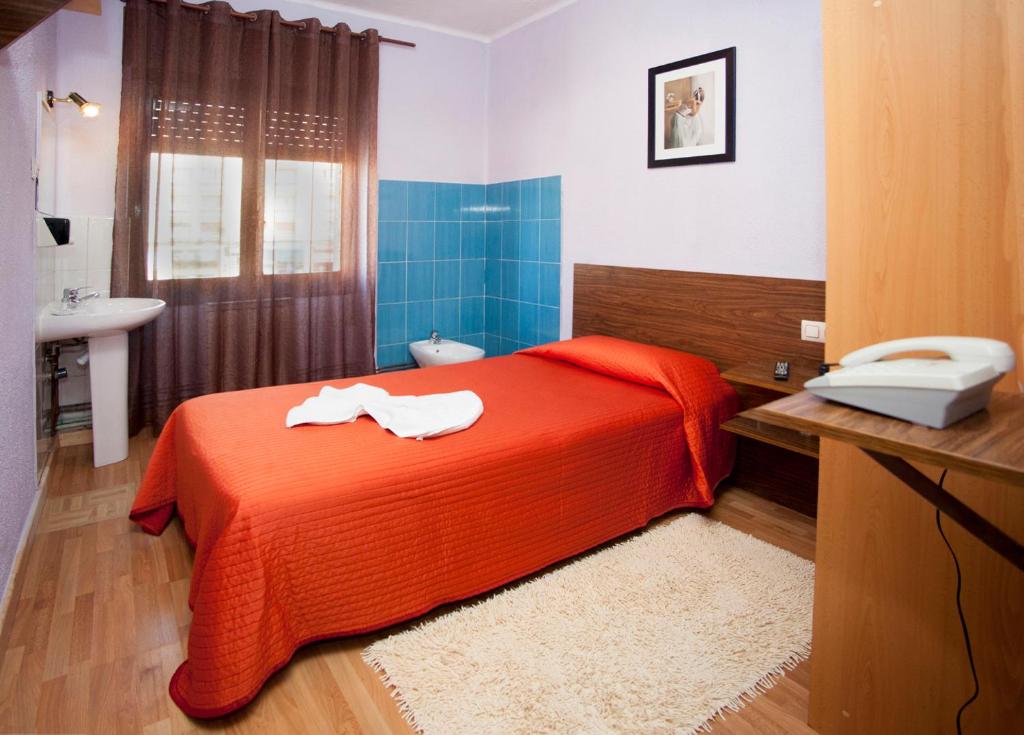 een slaapkamer met een rood bed en een wastafel bij Hostal Goias in Oviedo