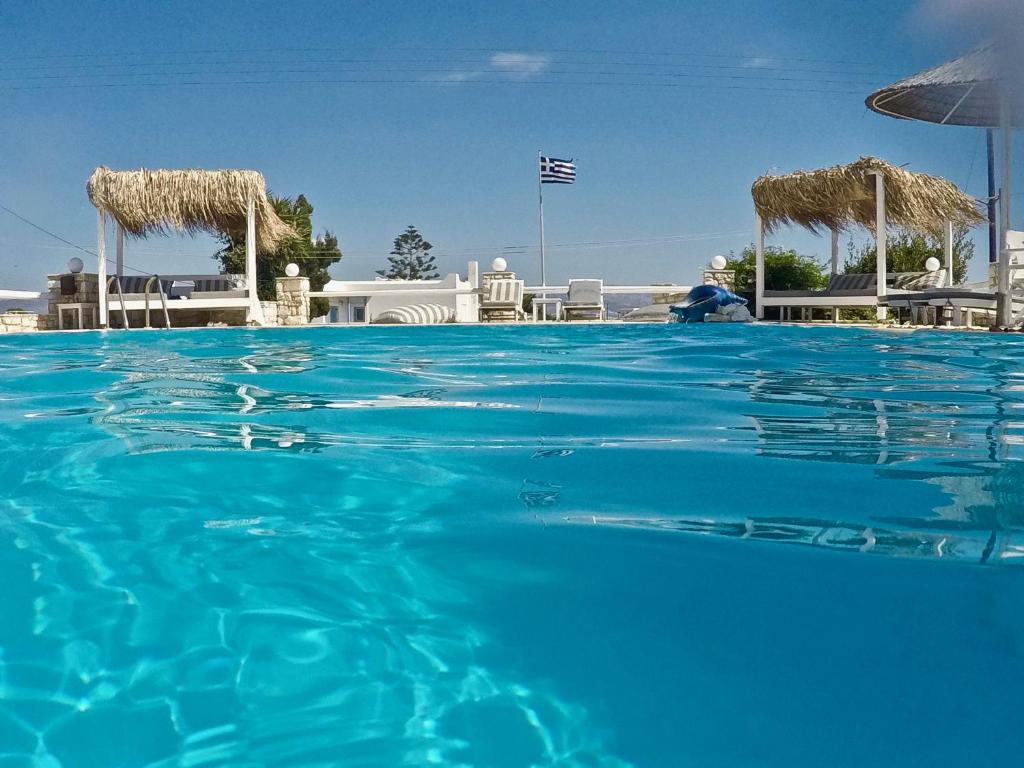 ein Pool mit blauem Wasser, Stühlen und Sonnenschirmen in der Unterkunft Margarita Studios Ambelas in Ampelas