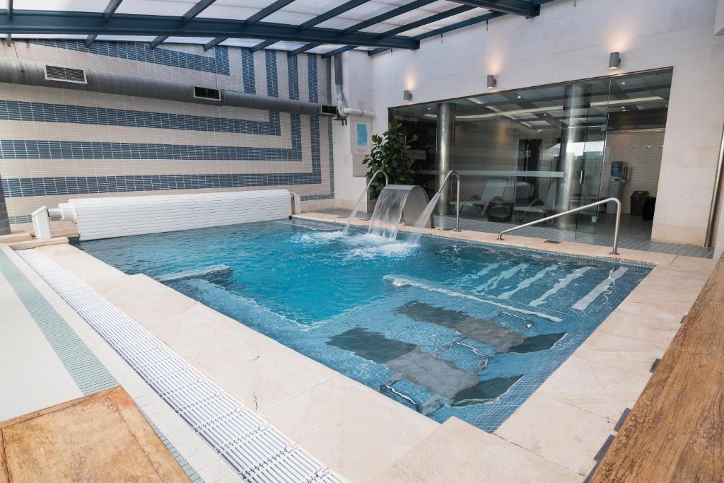 a swimming pool with a waterfall in a building at ARVA Spa París in León