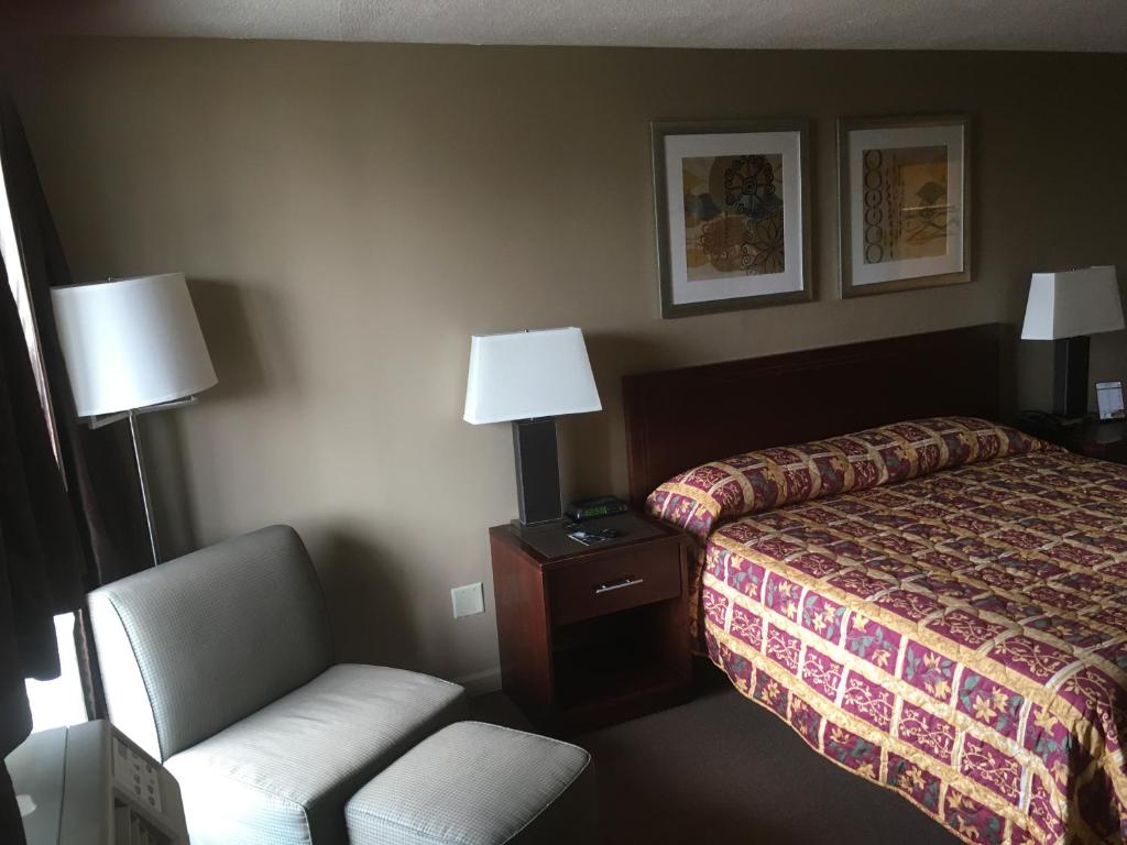 a hotel room with a bed and a chair at Allen Park Motor Lodge in Allen Park