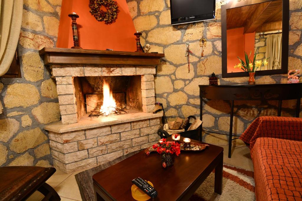 a living room with a stone fireplace with a table at XENIOS ZEYS (ΞΕΝΙΟΣ ΖΕΥΣ) in Synikia Mesi Trikalon