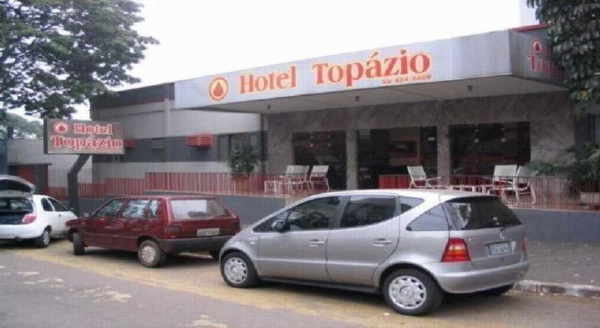 drei Autos auf einem Parkplatz vor einem Hotel Topota geparkt in der Unterkunft Hotel Topazio Ltda in Umuarama
