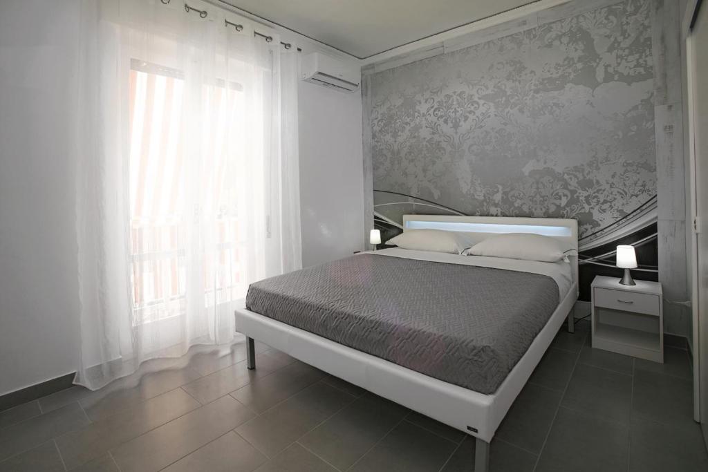 a white bedroom with a bed and a window at Enjoy Vida in Casola di Napoli