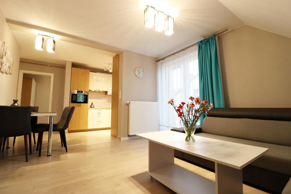 a living room with a couch and a table with flowers at Apartamenty BM'Kruk in Stronie Śląskie