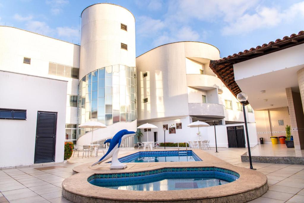 a pool in the courtyard of a building with a dolphin statue at Costa Atlantico Hotel in São Luís