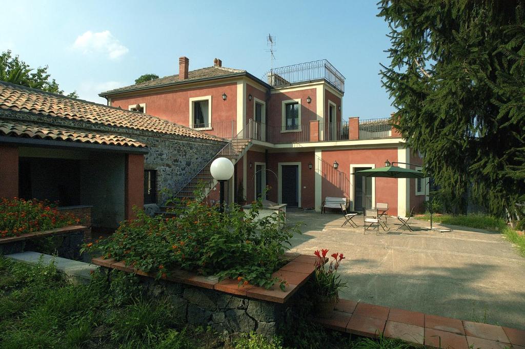 a large brick house with a yard with flowers at Antica Dimora Benanti in Milo