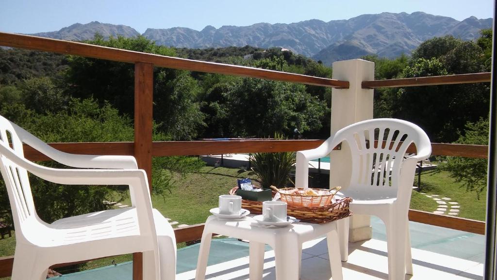 two white chairs and a table with a basket on a balcony at Cabañas Rincon Verde in Merlo