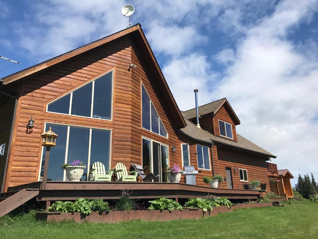 une maison en rondins avec une terrasse et des chaises. dans l'établissement Cozy Cove Inn, à Homer