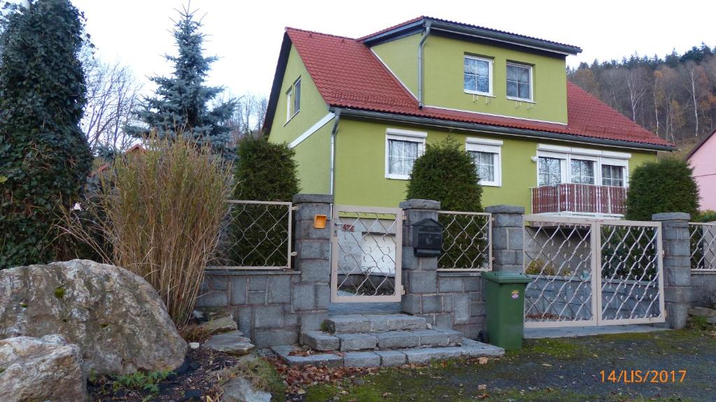 a yellow house with a gate and a fence at Apartman U Hanicky in Bělá pod Pradědem