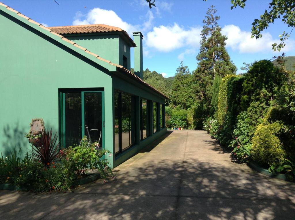 a green building with a walkway in front of it at Quinta de Santana - Queimadas in Furnas