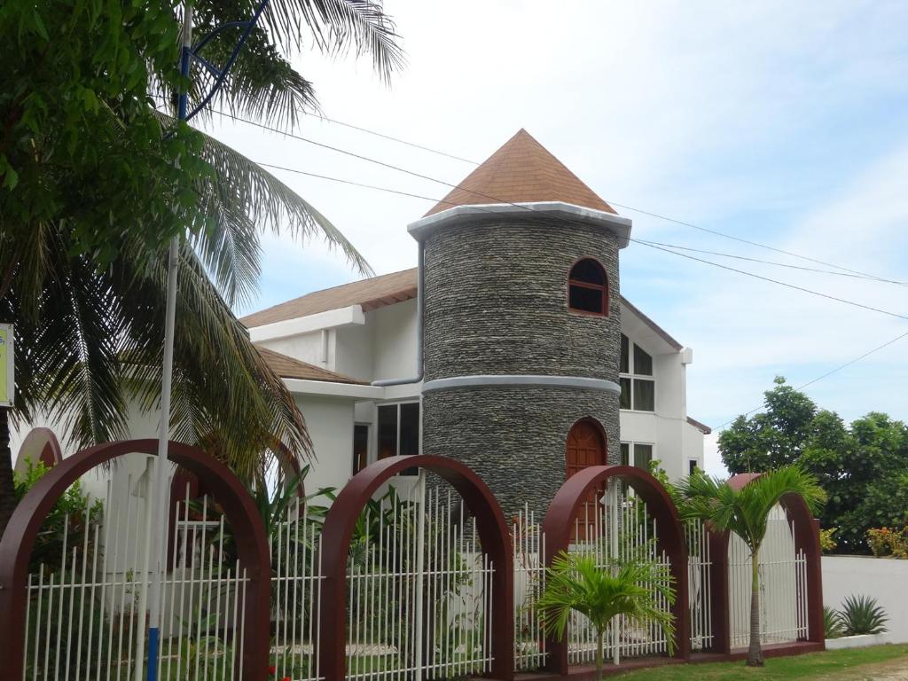 a white house with a brick tower behind a fence at House Rapunzel in Oslob