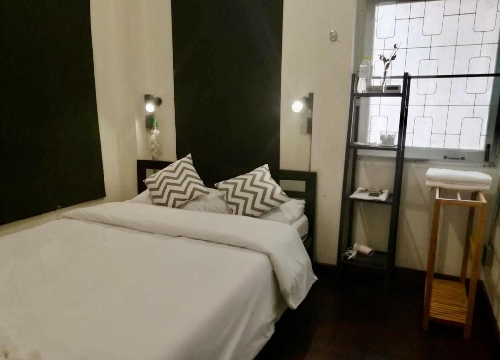 a bedroom with a bed with white sheets and pillows at Dreamcatcher Bangkok in Bangkok