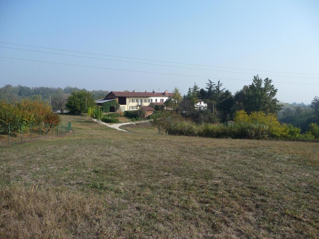 un grande campo con una casa sullo sfondo di B&B Cascina Bricchetto ad Asti