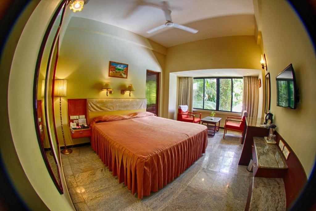een slaapkamer met een bed en een woonkamer bij Hotel Parisutham in Thanjāvūr