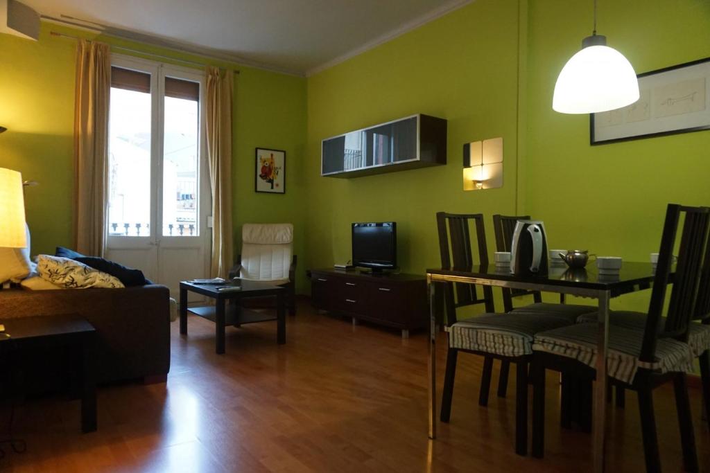 sala de estar con paredes verdes, mesa y sillas en ApartEasy - Montjuïc & Fira, en Barcelona